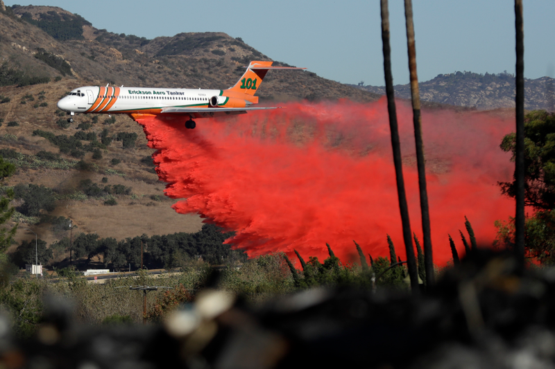 A plane drops fire retardant on a wildfire Friday, Dec. 8, 2017, in Fallbrook, Calif. Image: AP Photo/Gregory Bull